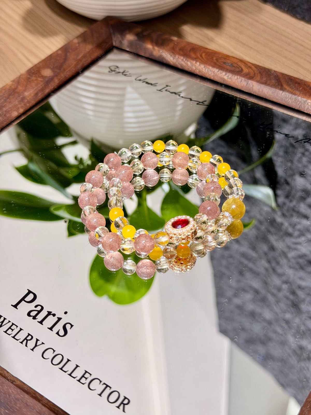 Honeyberry Gilt Bracelet double-loop coiled on a mirror with green leaves reflected