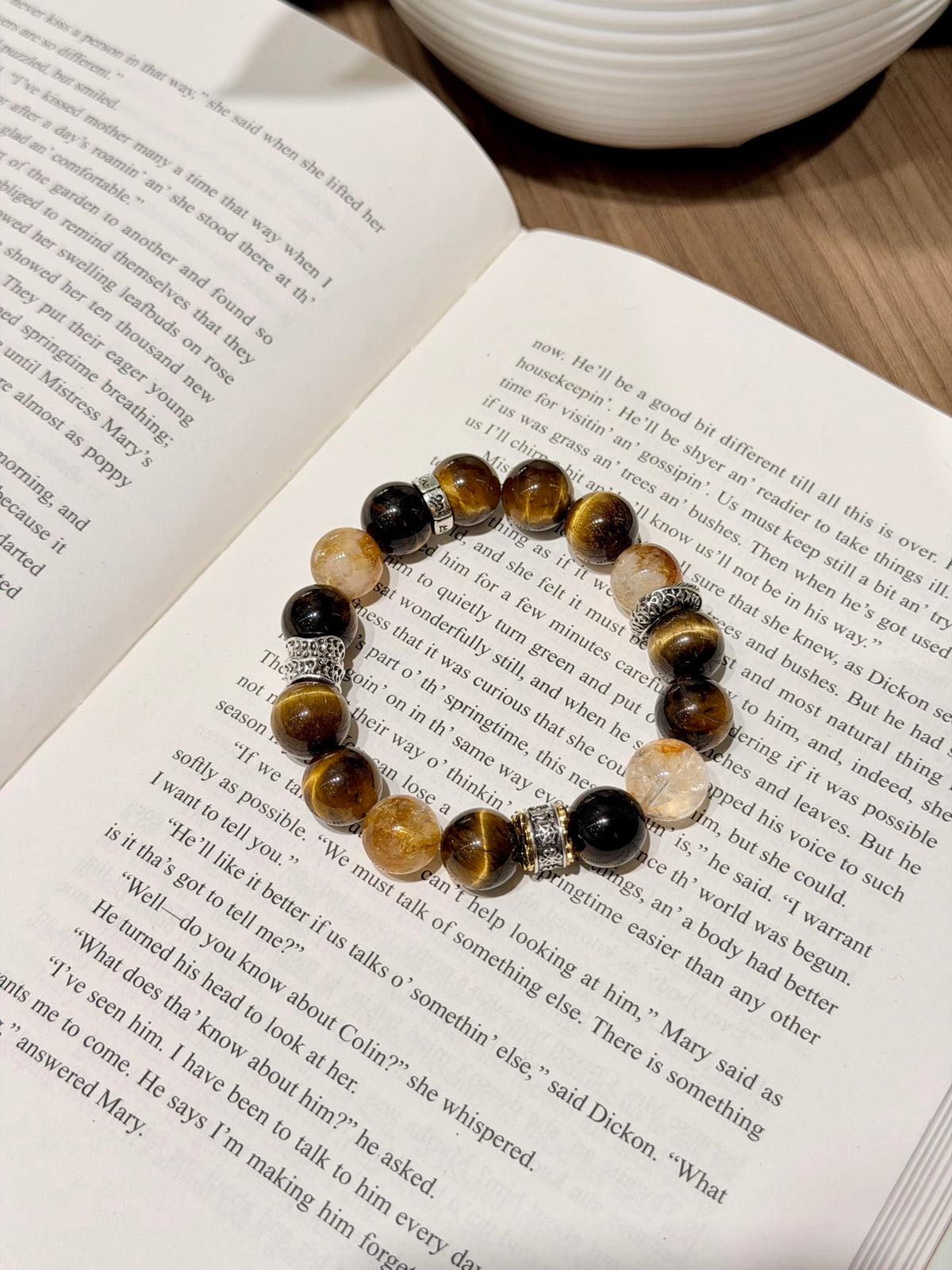 Golden Tiger Fortune Bracelet resting on an open book, men's bracelet with mantra beads