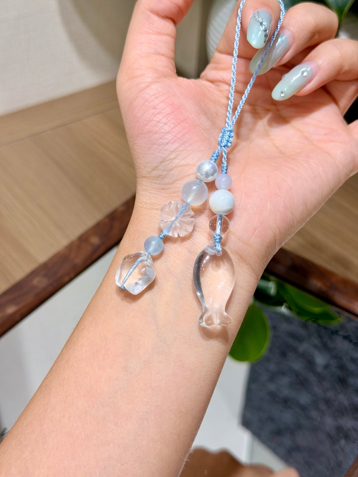 Ocean-themed crystal phone charm with carved fish held in a hand