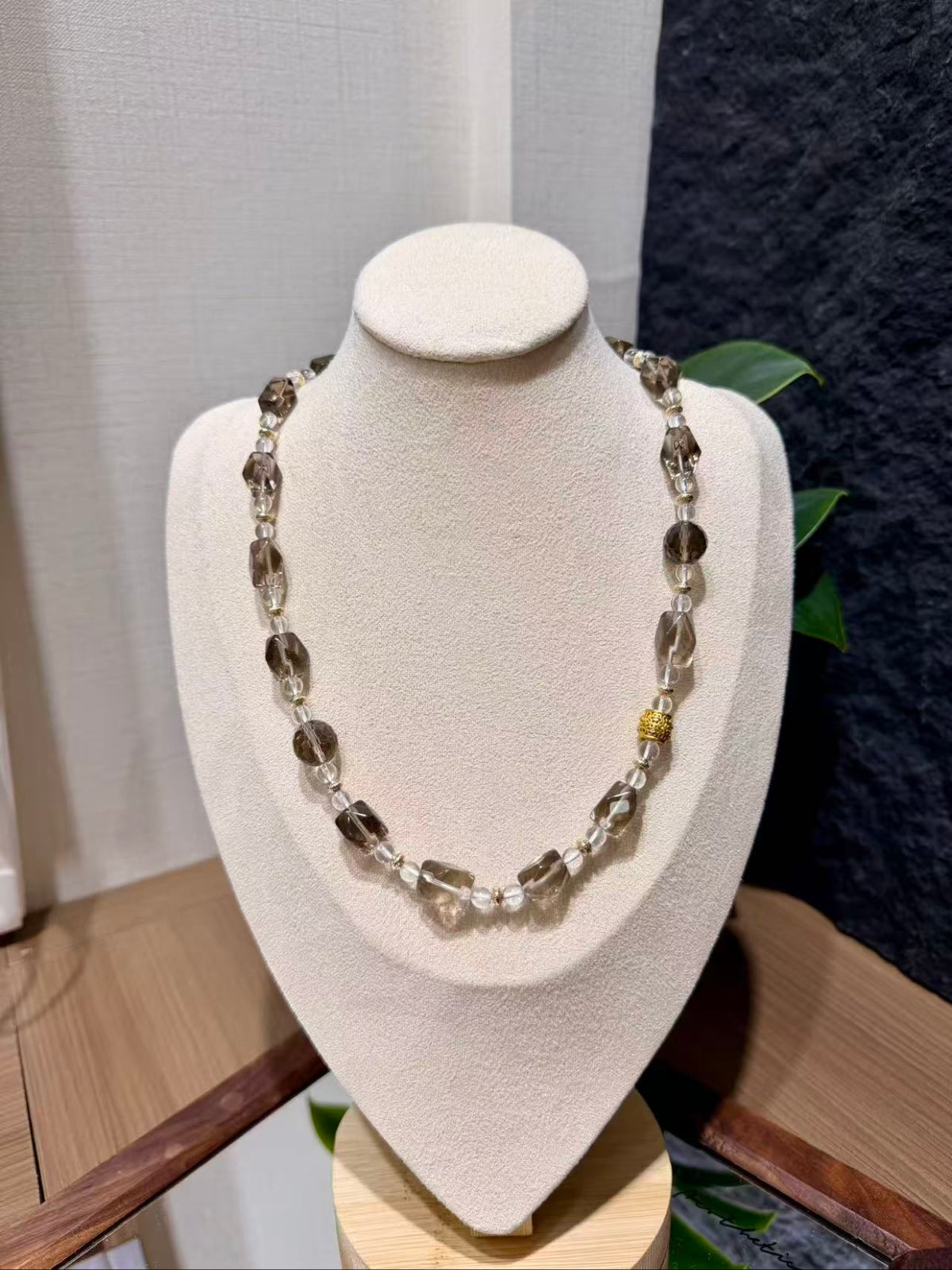 Smoky quartz beaded necklace displayed on a jewelry bust