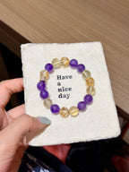 Purple and gold prologue natural crystal bracelet with amethyst and gold-foil flower crystal beads in a circle on a Have a nice day card