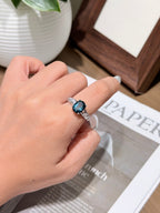 Deep teal topaz solitaire ring with 18K gold plated setting worn on a finger