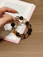 Special design multi-gemstone bracelet held over an open book