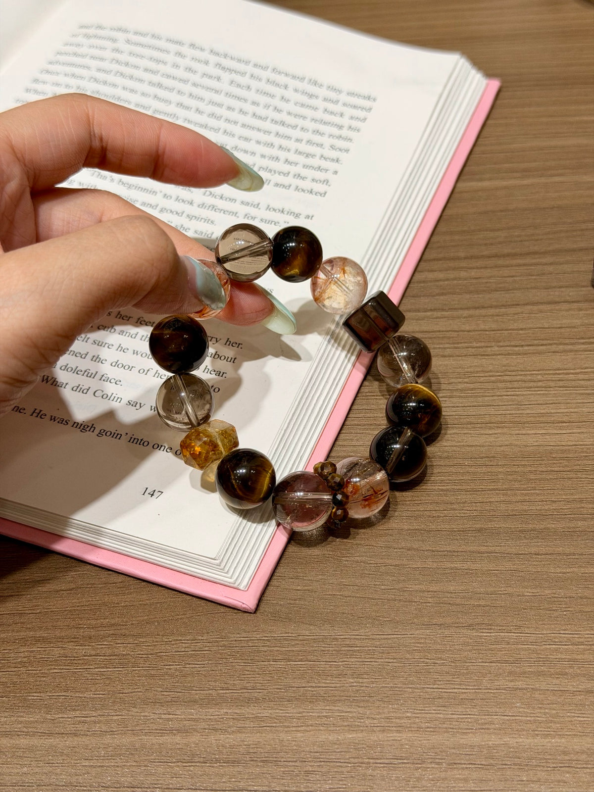 Special design multi-gemstone bracelet held over an open book