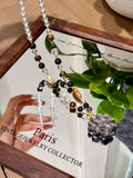 Obsidian and sandalwood beaded necklace with fox pendant over a mirror