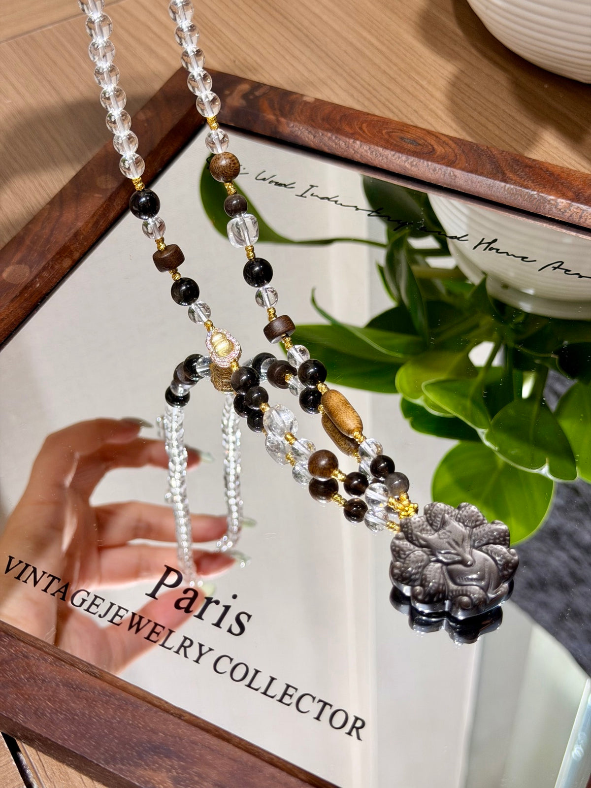 Obsidian and sandalwood beaded necklace with fox pendant over a mirror