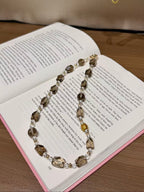 Smoky quartz and clear quartz beaded necklace laid on an open book