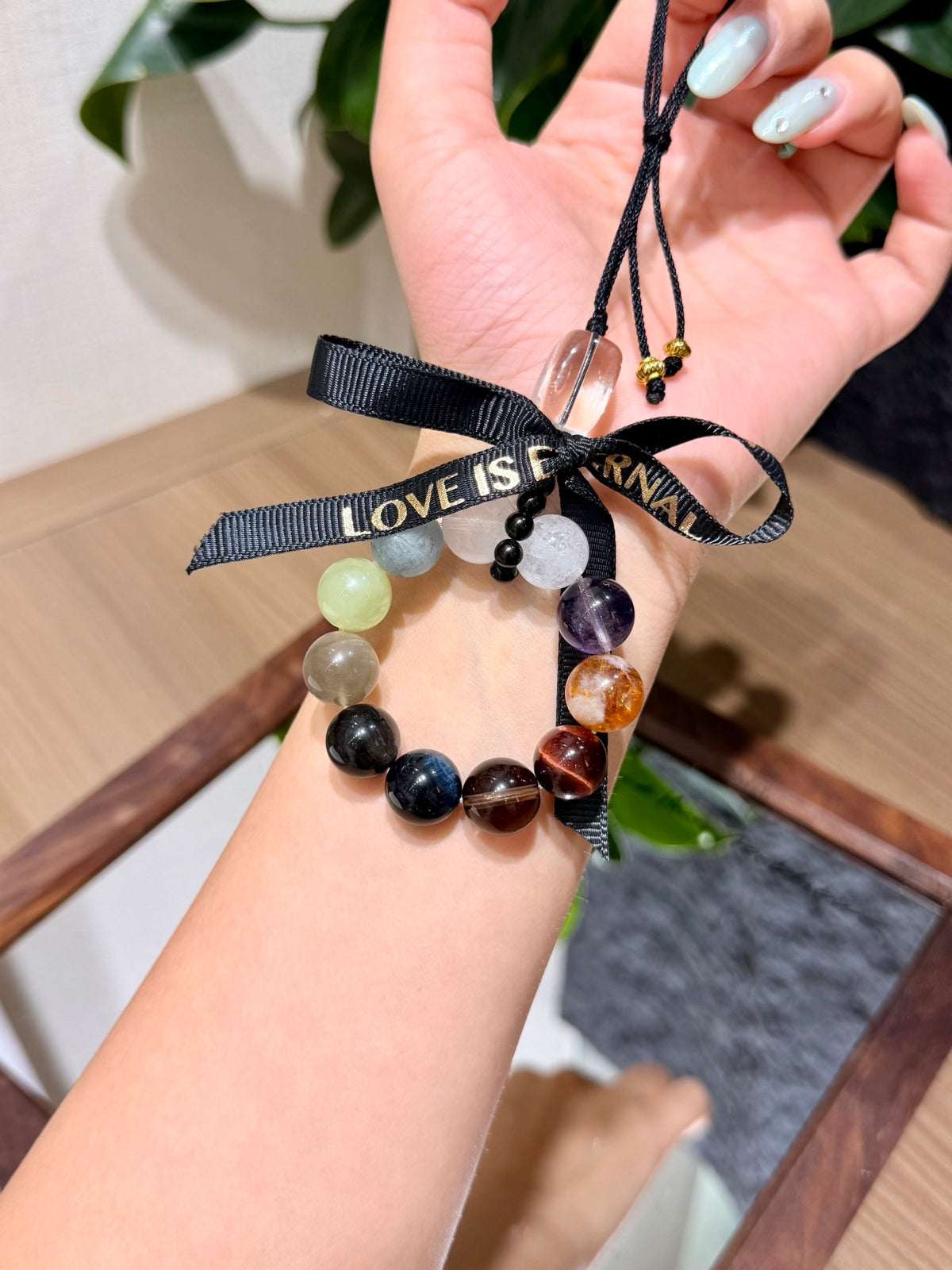 Multi-gemstone car charm with ribbon bow held in a hand