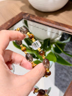 Golden tiger's eye bracelet with smoky quartz candy beads held over a mirror