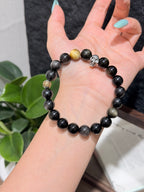 Black Gold Armor Bracelet held in hand, silver sheen obsidian with golden tiger's eye bead