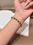 Golden brown shimmer natural crystal bracelet with yellow tiger's eye beads worn on a wrist with an open book in the background