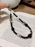 Black obsidian and pearl bag charm with metal clasp on an open book