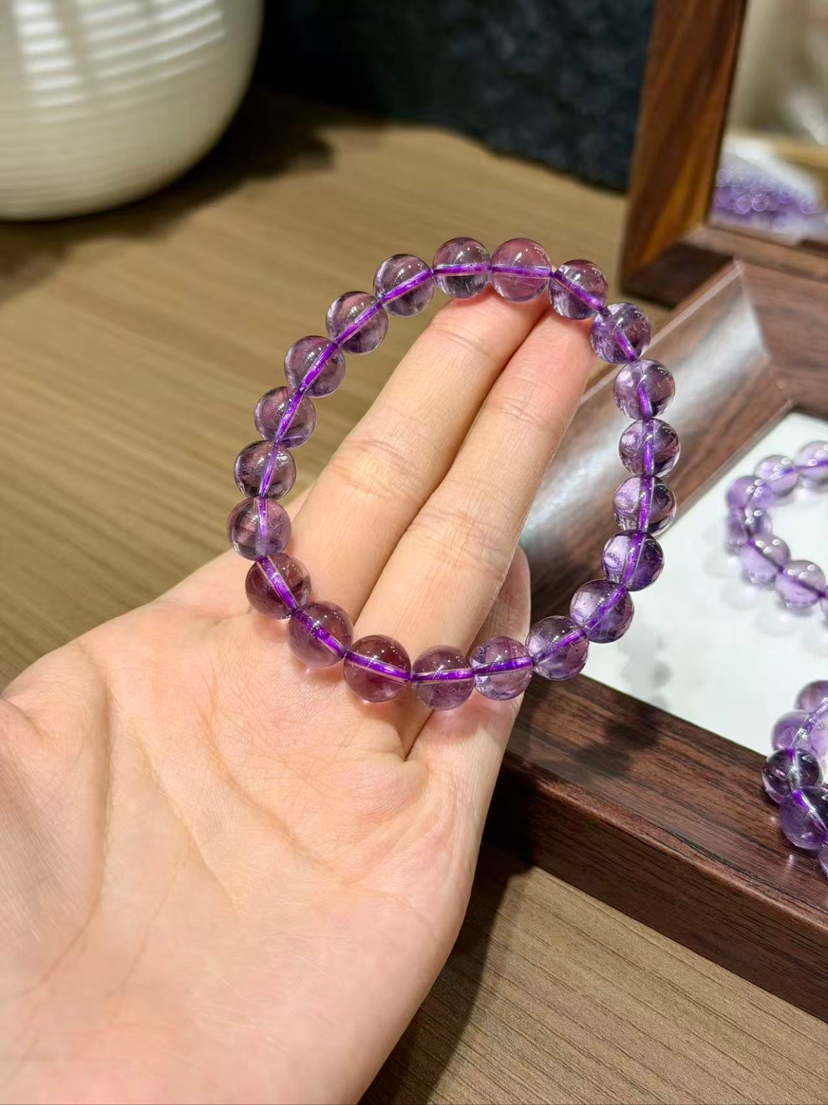 Regal Amethyst Bracelet held up, violet amethyst beads with mirror reflection