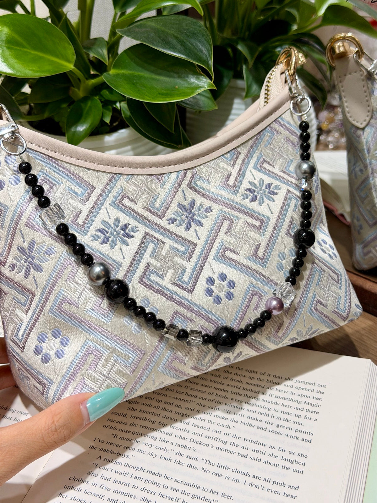 Black beaded bag chain with clear quartz cubes on a book