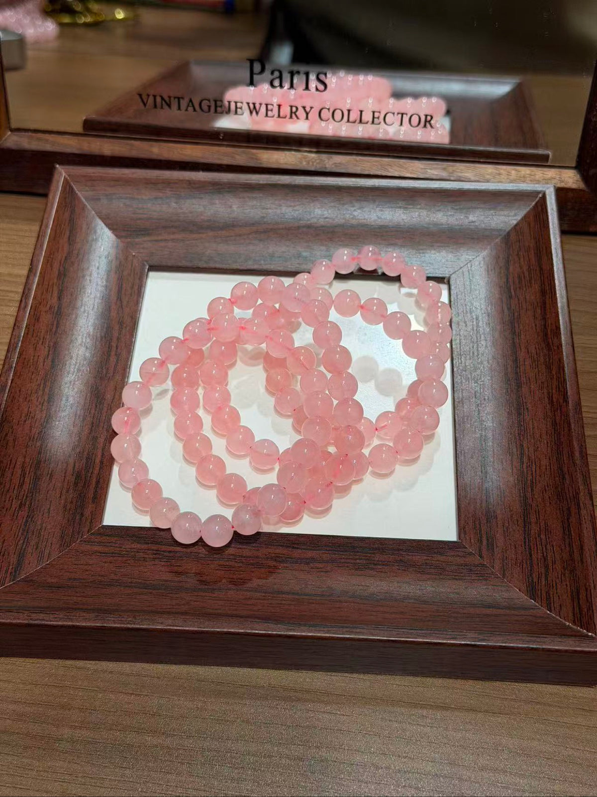 Blush Grapefruit Bracelet coiled in a wooden tray, blush-grapefruit pink quartz beads