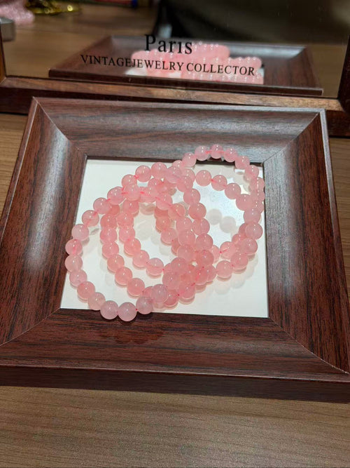 Blush Grapefruit Bracelet coiled in a wooden tray, blush-grapefruit pink quartz beads