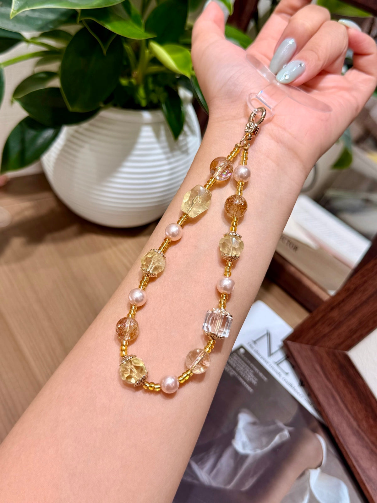 Golden citrine phone charm draped over a wrist