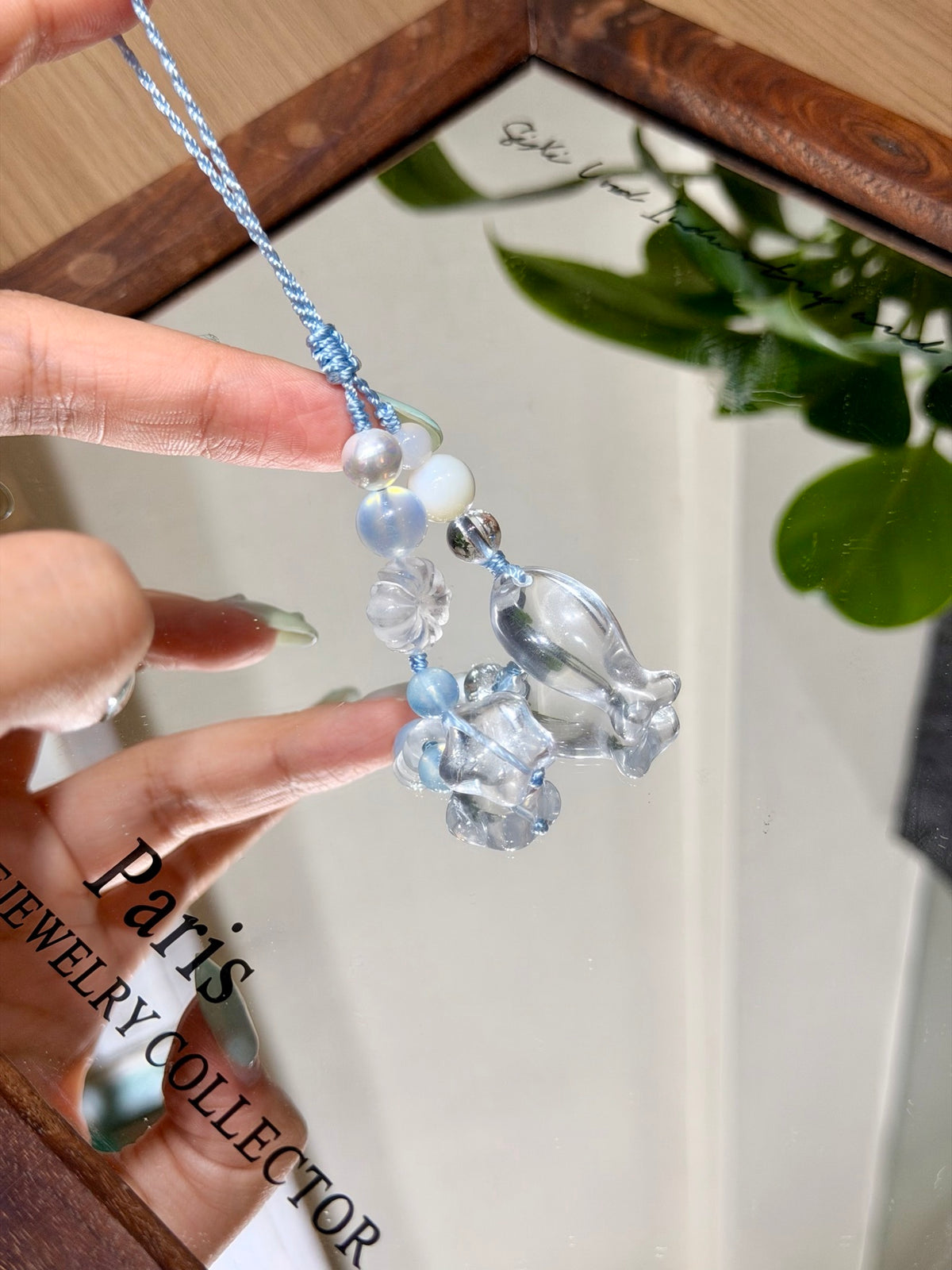 Aquamarine phone charm with shell beads over a mirror