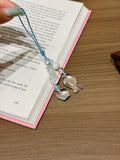 Aquamarine and clear quartz phone charm with fish, star, and clover carvings on an open book