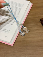 Aquamarine and clear quartz phone charm with fish, star, and clover carvings on an open book