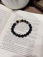 Black Gold Armor Bracelet held above the wrist, skull charm and gold accent bead