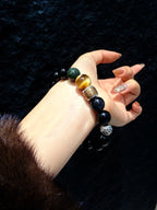 Obsidian Guardian Bracelet held in hand, black beads with gold mantra bead
