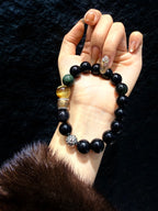 Obsidian Guardian Bracelet on wrist against dark background, golden tiger's eye and green rutilated quartz beads