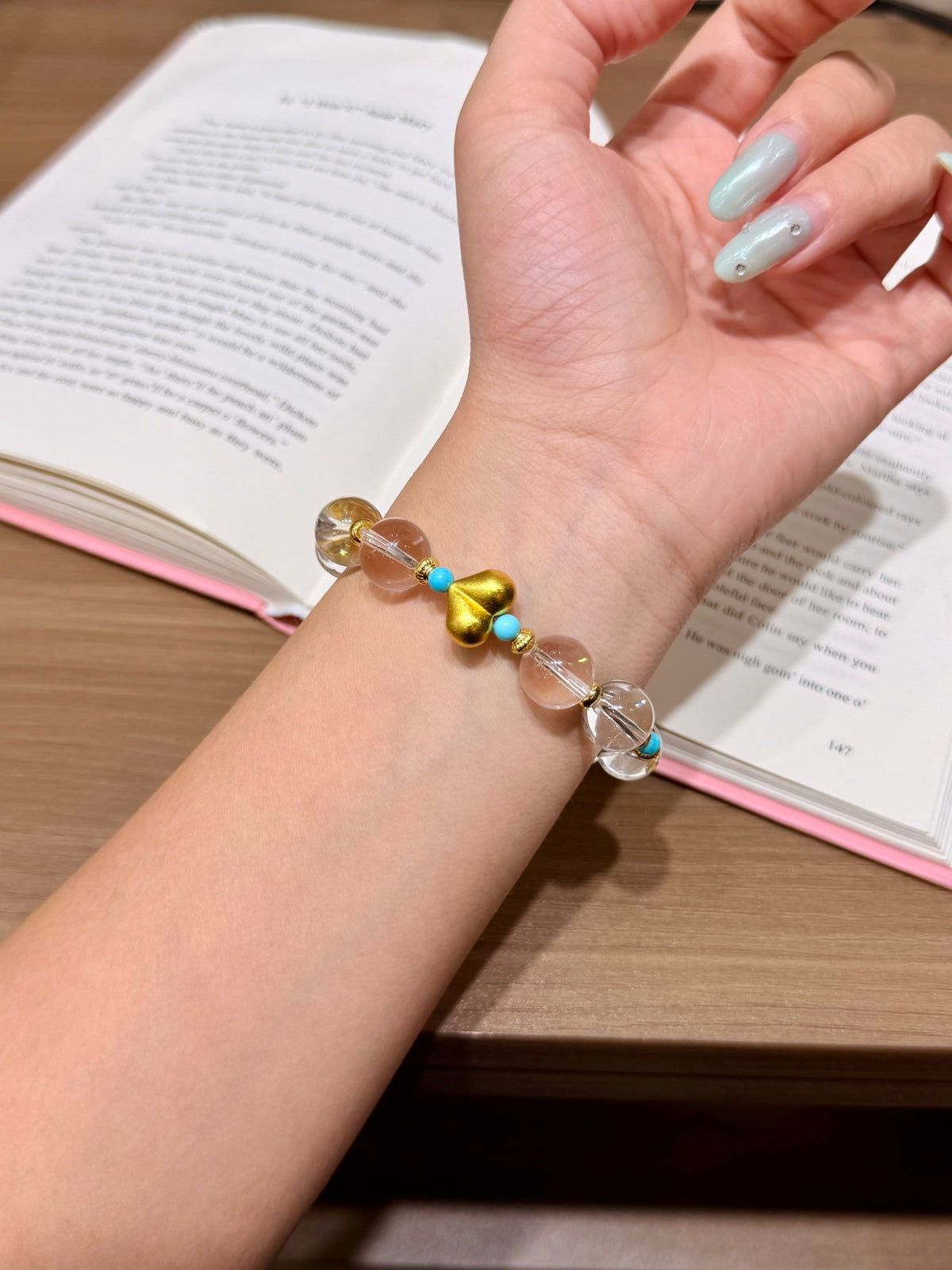 Sea-salt blue crystal bracelet with gold heart worn on a wrist