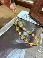 Gold-foil quartz phone charm with metal clasp over a magazine