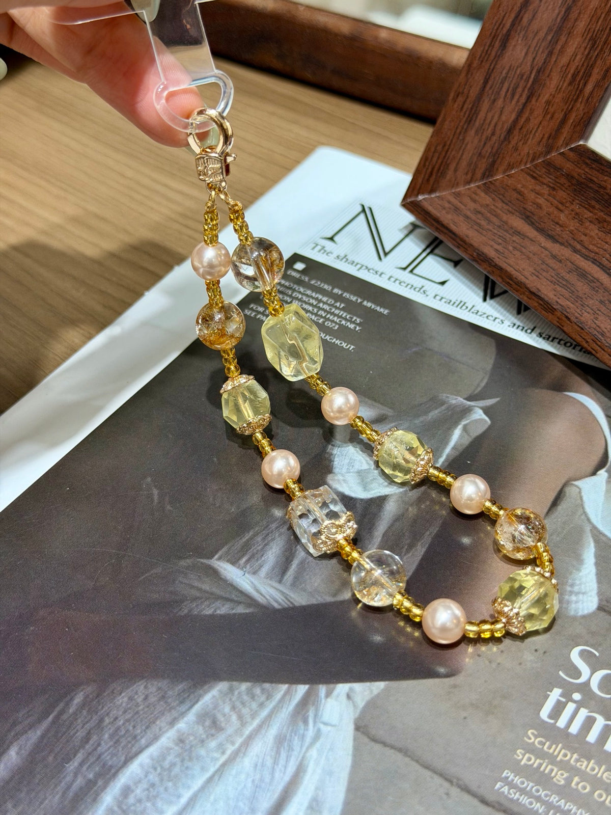 Gold-foil quartz phone charm with metal clasp over a magazine