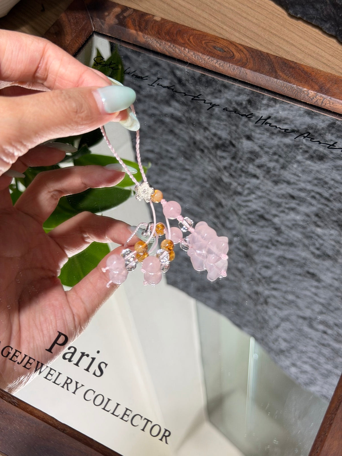 Pink quartz bear phone charm with flower charms over a mirror