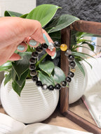 Black Gold Armor Bracelet resting on an open book, men's black and gold bracelet