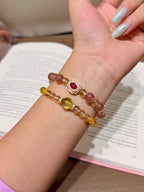 Honeyberry Gilt Bracelet worn on wrist, double-loop with gold-set red gemstone charm