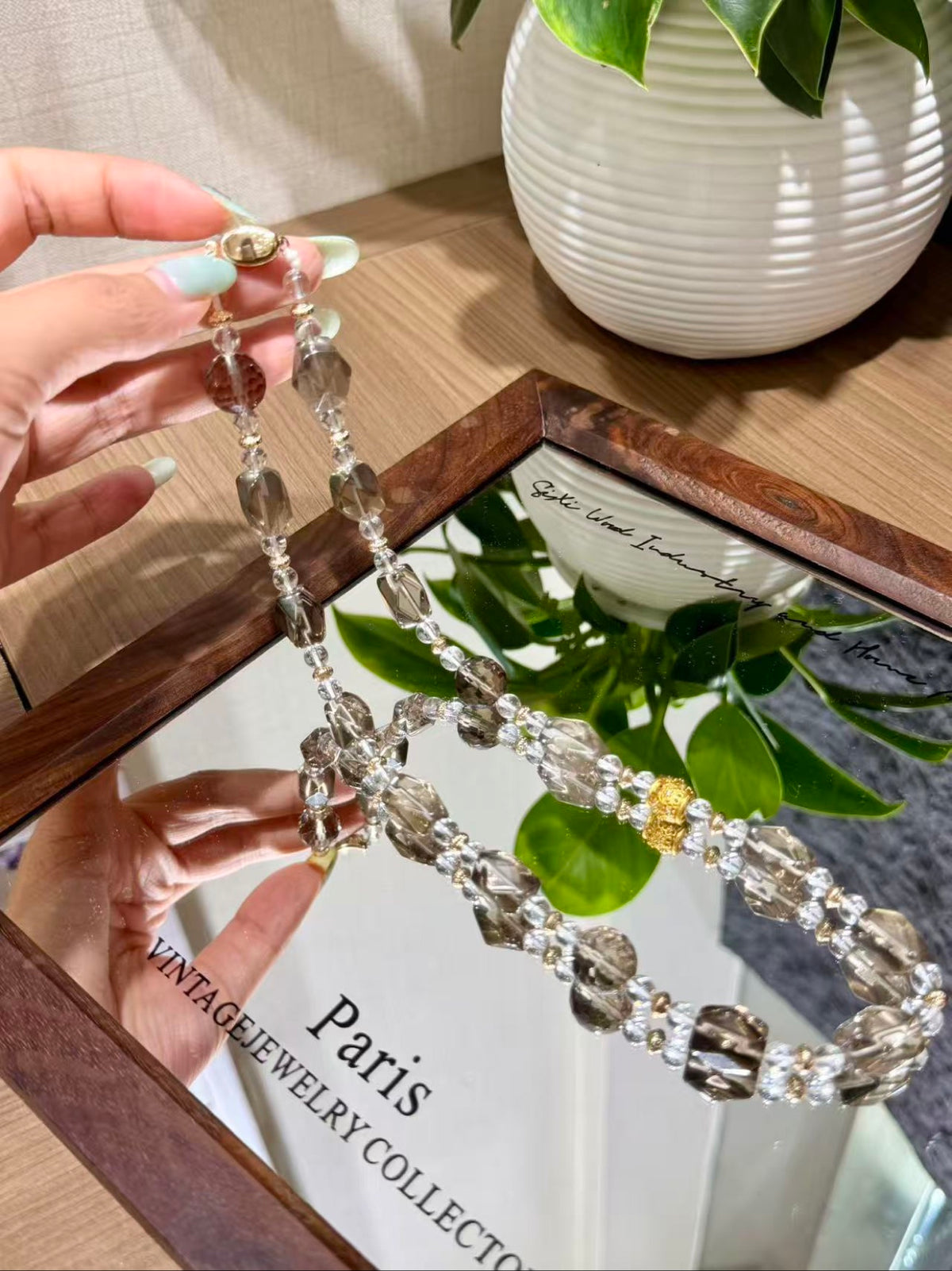 Smoky quartz necklace with faceted beads held in a hand