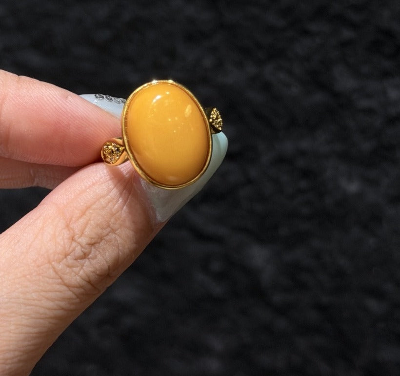 Honey amber ring with sparkling accent shoulders worn on a finger