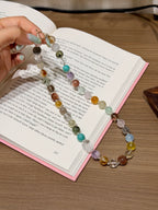 Rainbow gemstone bead necklace with pixiu charm laid on an open book