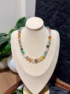 Colorful multi-gemstone bead necklace displayed on a jewelry bust