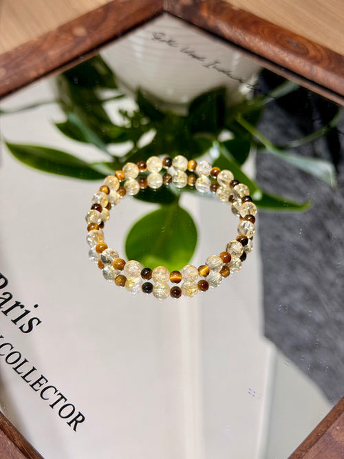 Golden brown shimmer natural crystal bracelet with yellow tiger's eye beads in circular flat-lay beside a book