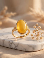 Honey amber solitaire ring on a marble tray with dried flowers