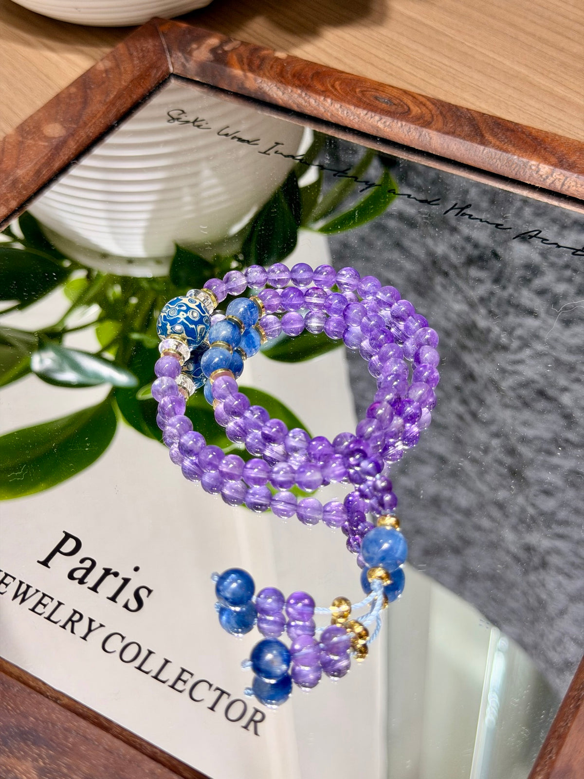 Coiled amethyst kyanite bracelet with blue lacquer accent bead on mirrored tray