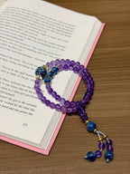 Amethyst kyanite bracelet resting on open book beside the lacquer focal bead