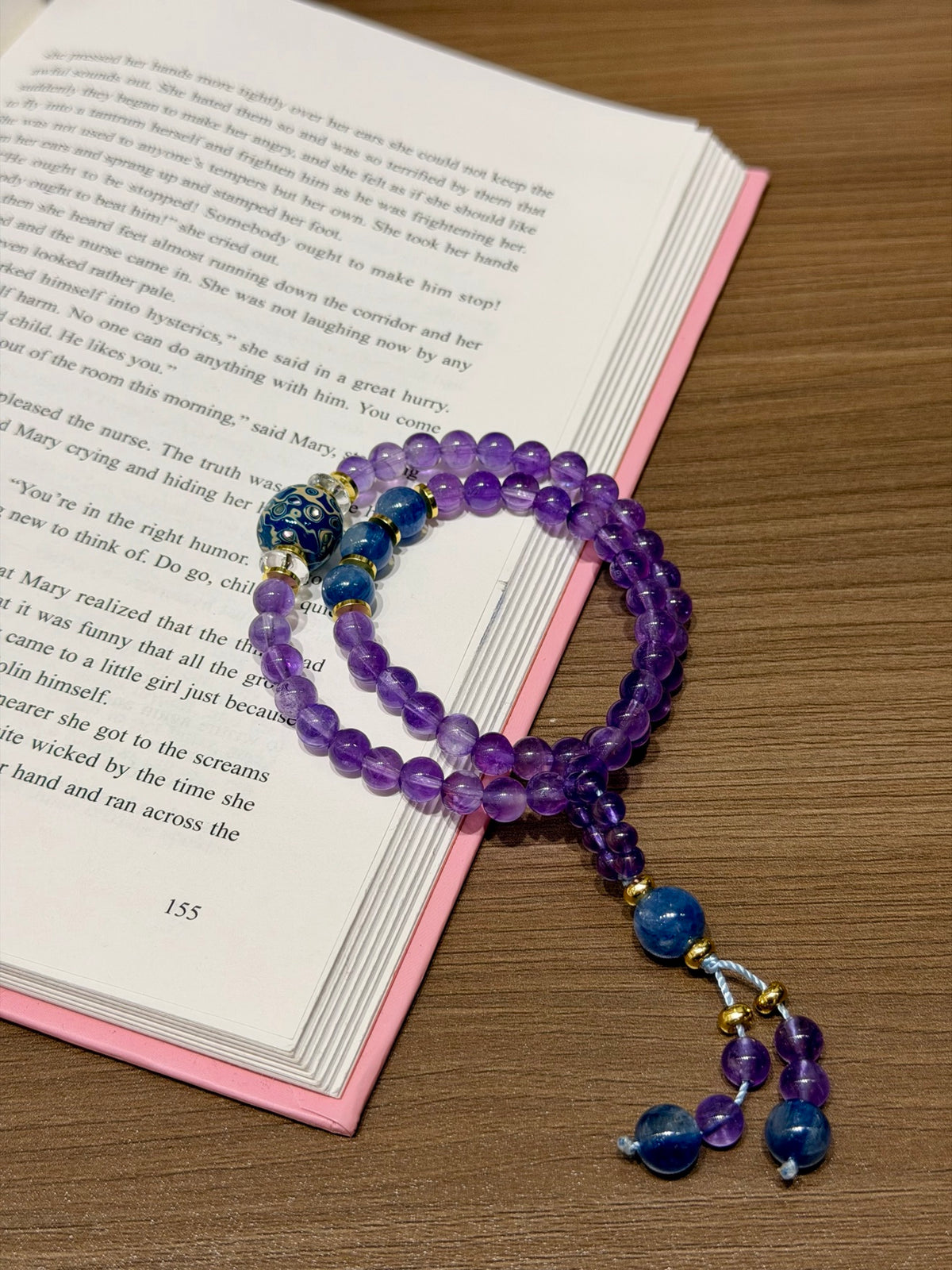 Amethyst kyanite bracelet resting on open book beside the lacquer focal bead